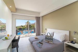 a bedroom with a bed and a view of a pool at Cathrin Hotel in Faliraki