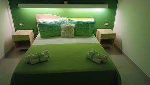 una camera verde con un grande letto con lenzuola e cuscini verdi di Il giardino dei tramonti a Nardò