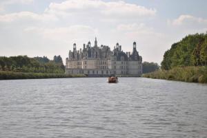 eine Burg inmitten eines Flusses mit einem Boot in der Unterkunft LE GITE in Bracieux