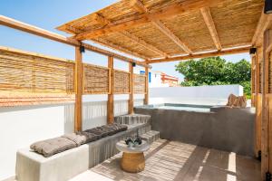 a patio with a hot tub and a wooden pergola at House Marigo Suites in Koskinou