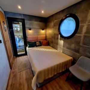 a small bedroom with a bed and a round window at Apartament na wodzie Augustów in Augustów