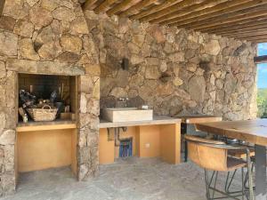 cocina con pared de piedra, fregadero y mesa en VILLA privée 3 étoiles avec piscine, jardin et terrain de pétanque en Lecci