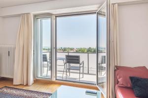 a living room with a balcony with a red couch at Lake View See & Bergsicht free parking in Kreuzlingen