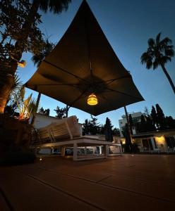 eine Bank mit einem großen Regenschirm auf einer Straße in der Unterkunft Banus Lodge in Marbella