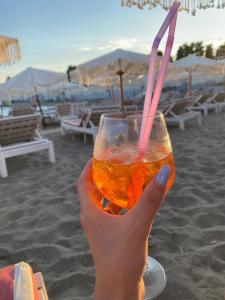 a hand holding a drink with a straw on the beach at Shtepipushimi23 Rana e Hedhun in Shëngjin