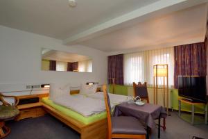 Hotel Goldene Sonne في آرنشتات: غرفة بسرير وطاولة وتلفزيون