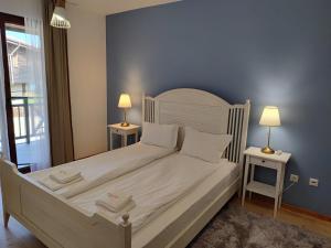Sozopolis Holiday Village في سوزوبول: غرفة نوم بسرير ابيض كبير مع طاولتين