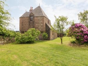 an old brick building with a tree in the yard at Holly Leaf Cottage - Drum Castle Estate in Banchory