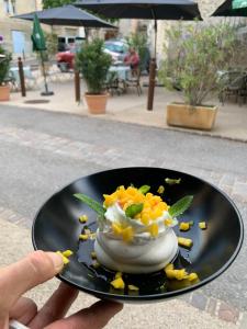 una persona sosteniendo un postre en un plato negro en L’OBSERVATOIRE en Saint-Michel-lʼObservatoire