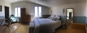 um quarto com uma cama, uma secretária e janelas em L’OBSERVATOIRE em Saint-Michel-lʼObservatoire
