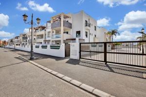 a white building with a fence next to a street at 2 terraces apartment w/ astonishing views. in Costa de Antigua