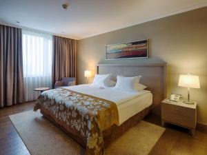 um quarto de hotel com uma cama grande num quarto em Ramada Plaza By Wyndham Kahramanmaras em Karamamaras