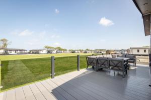 una terraza con mesa, sillas y un campo en Stewarts Resort Lodge 76 en St Andrews
