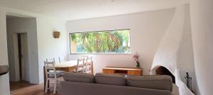 een woonkamer met een bank, een tafel en een raam bij Casas da Barra in Praia de Mira