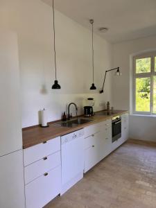 a kitchen with white cabinets and a sink at Idyllisches Appartement nahe Ostsee und Schlei in Rabenkirchen-Faulück