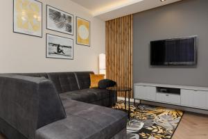 Stunning Family Apartment Ursynów with Parking & Balcony by Noclegi Renters في وارسو: غرفة معيشة مع أريكة وتلفزيون بشاشة مسطحة