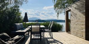 un patio con mesa y sillas y vistas al agua en Naturel Chalet am Faaker See, en Faak am See