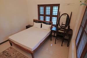 a bedroom with a bed and a desk and a mirror at Serenity Villa and Treehouse in Palakkad