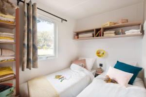 1 dormitorio con 2 camas y ventana en Camping Le Fou du Roi, en Lansargues