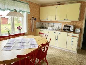 uma cozinha com uma mesa de madeira e um micro-ondas em Cozy red cottage in the countryside outside Vimmerby em Gullringen