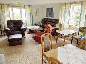 uma sala de estar com mobiliário de couro e mesas e cadeiras em Cozy red cottage in the countryside outside Vimmerby em Gullringen