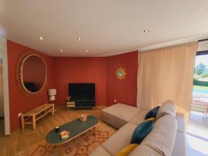 a living room with a couch and a tv at Villa 5 étoiles piscine chauffée 8 pers 'Casa Sista' by Casa FAMILIA Ardèche in Sampzon