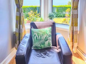 a leather chair in front of a window with a pillow at Firwood Apartment in Kilmun