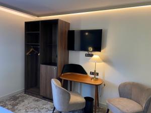 a hotel room with a desk and chairs and a tv at Lancelot & Spa - Domaine du Roi Arthur in Ploërmel