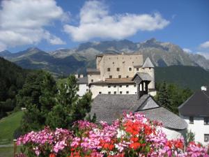 ein Schloss auf einem Hügel mit Blumen in der Unterkunft Alpenrose-Apart in Nauders