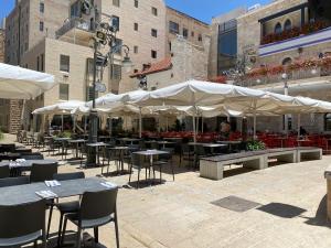 eine Terrasse mit Tischen, Stühlen und weißen Sonnenschirmen in der Unterkunft GoodHouse 402 - 4 Bdr beautiful apartment in Jerusalem in Jerusalem