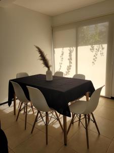 een eetkamer met een zwarte tafel en witte stoelen bij Lujoso apartamento cómodo y luminoso con seguridad 24 hs y estacionamiento in Guaymallen