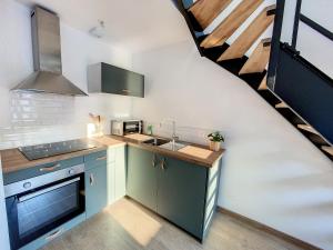 a kitchen with blue cabinets and a staircase at Au Duplex indus/chic de Breteuil in Breteuil