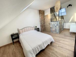 a bedroom with a white bed and a brick wall at Au Duplex indus/chic de Breteuil in Breteuil