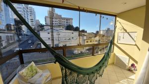 a hammock on a balcony with a view of a city at APTO DON JUAN NO CENTRO DA CIDADE in Bento Gonçalves