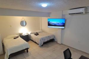 1 dormitorio con 1 cama y TV en la pared en Departamento ( j ) Comodo centrico Tv Ac wifi cocina parking, en Ciudad Valles