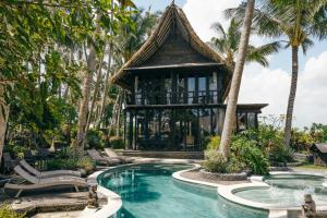 a resort pool with a gazebo and palm trees at Beachfront Villa Nixie and the Sea in Tabanan