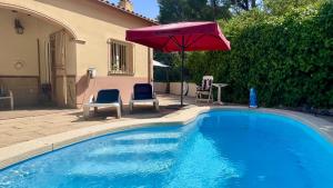 a swimming pool with two chairs and an umbrella at Villa Pineda 5 in Pals