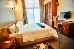 アルーシャにあるseven skies hotelのベッドと机とテレビのある寝室