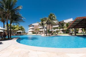 a large swimming pool with palm trees and buildings at Paraíso das Dunas Pé na Areia 2 Suítes 6 Pessoas in Aquiraz