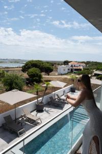 a woman standing on the balcony of a hotel at Ria Formosa Guest House in Faro