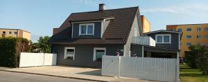 mały czarny dom z białym płotem w obiekcie Liisu Külalistemaja w mieście Haapsalu