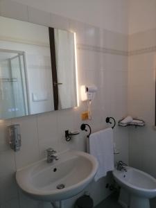 Baño blanco con lavabo y espejo en Casa Laghetto en Castellaro