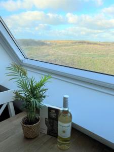 una botella de vino sentada en una mesa junto a una ventana en Moana, en Egmond aan Zee