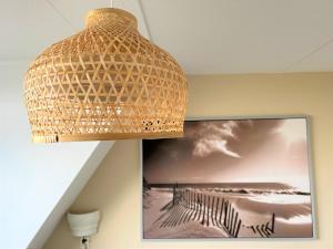 a wicker light hanging from a ceiling with a picture at Moana in Egmond aan Zee