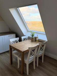 comedor con mesa, sillas y ventana en Moana, en Egmond aan Zee