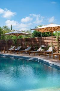 a swimming pool with chairs and umbrellas at Lou Cagnard in Saint-Tropez
