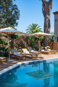a pool with chairs and umbrellas next to a tree at Lou Cagnard in Saint-Tropez