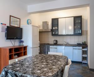 a kitchen with a table and a white refrigerator at Apartments Corny in Pag