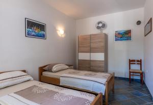 a bedroom with two beds and a chair at Apartments Corny in Pag