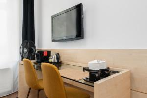 a dining room table with chairs and a television on a wall at Matejki- Brokatowy in Poznań